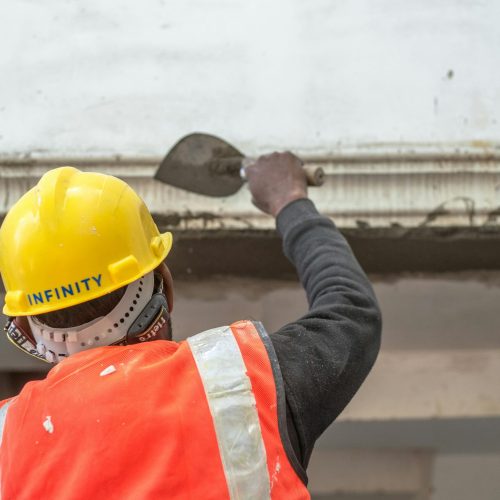 A construction worker in safety gear renovating an interior wall in Delhi, India.